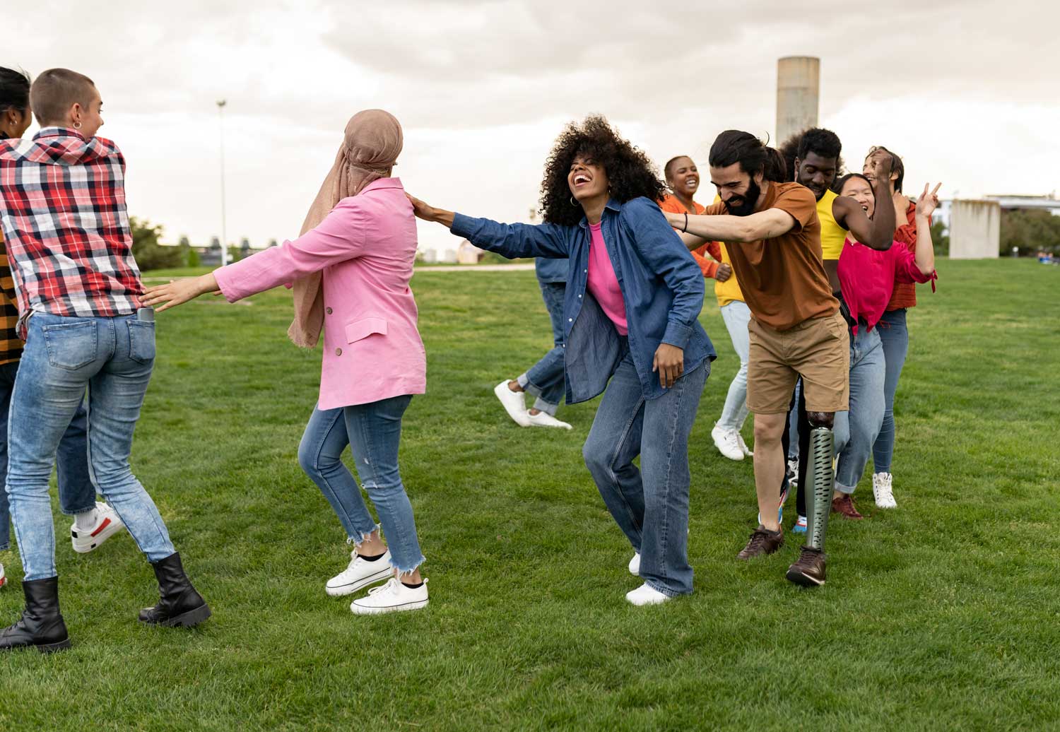 Joyful group of diverse people holding hands and dancing in a field.