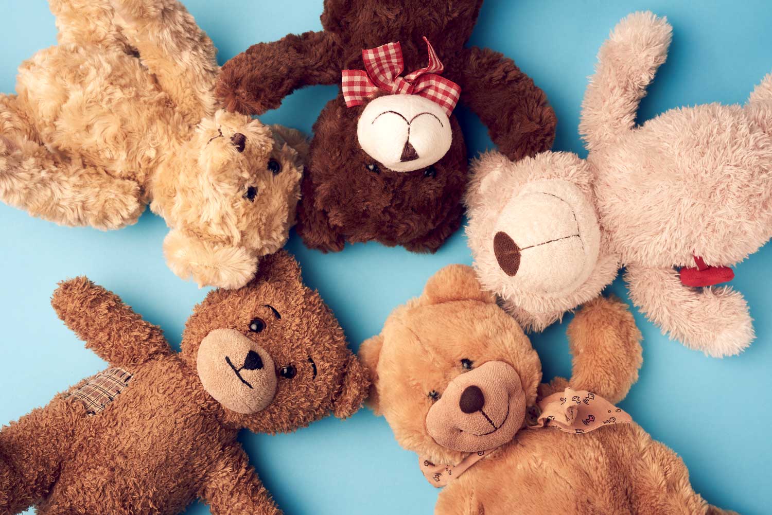 Circle of various teddy bears on a blue background.