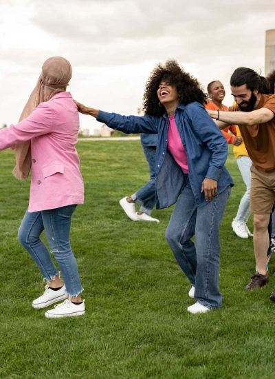 Joyful group of diverse people holding hands and dancing in a field.